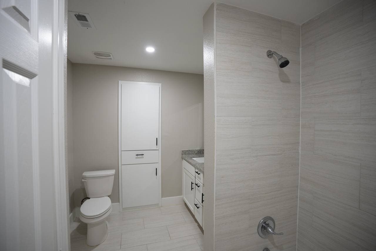 Full bathroom remodel with tiled shower and granite vanity